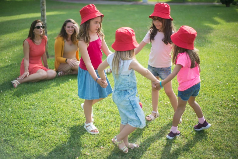 children wearing hats while walking in a field