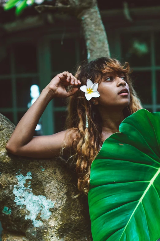 woman with long brown hair holding a leaf on palm tree