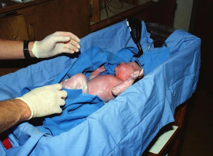 a person is working on a baby doll with a blue blanket