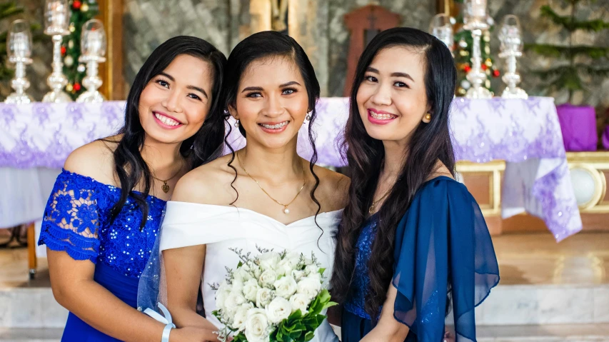 a woman in a blue and white dress poses with two another women