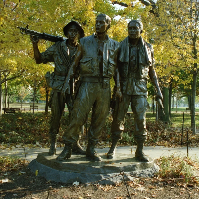 three bronze colored soldiers standing in front of a tree
