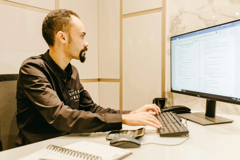 a man works on his desktop computer and a mouse