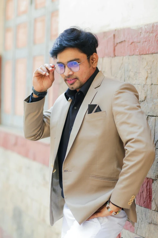 a man in suit leaning against a brick wall