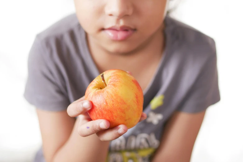 the little girl is holding an apple in her hands