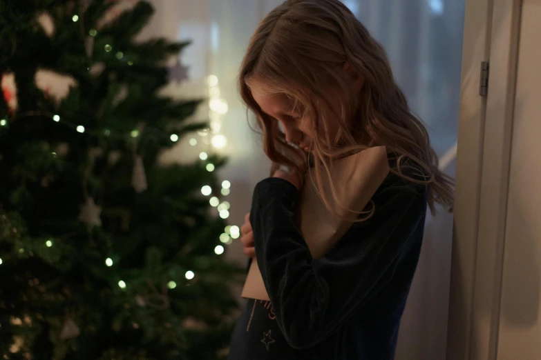 a woman is standing by a christmas tree