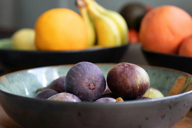 a bowl of fruit with an orange, banana, tangerine and an apple in the background