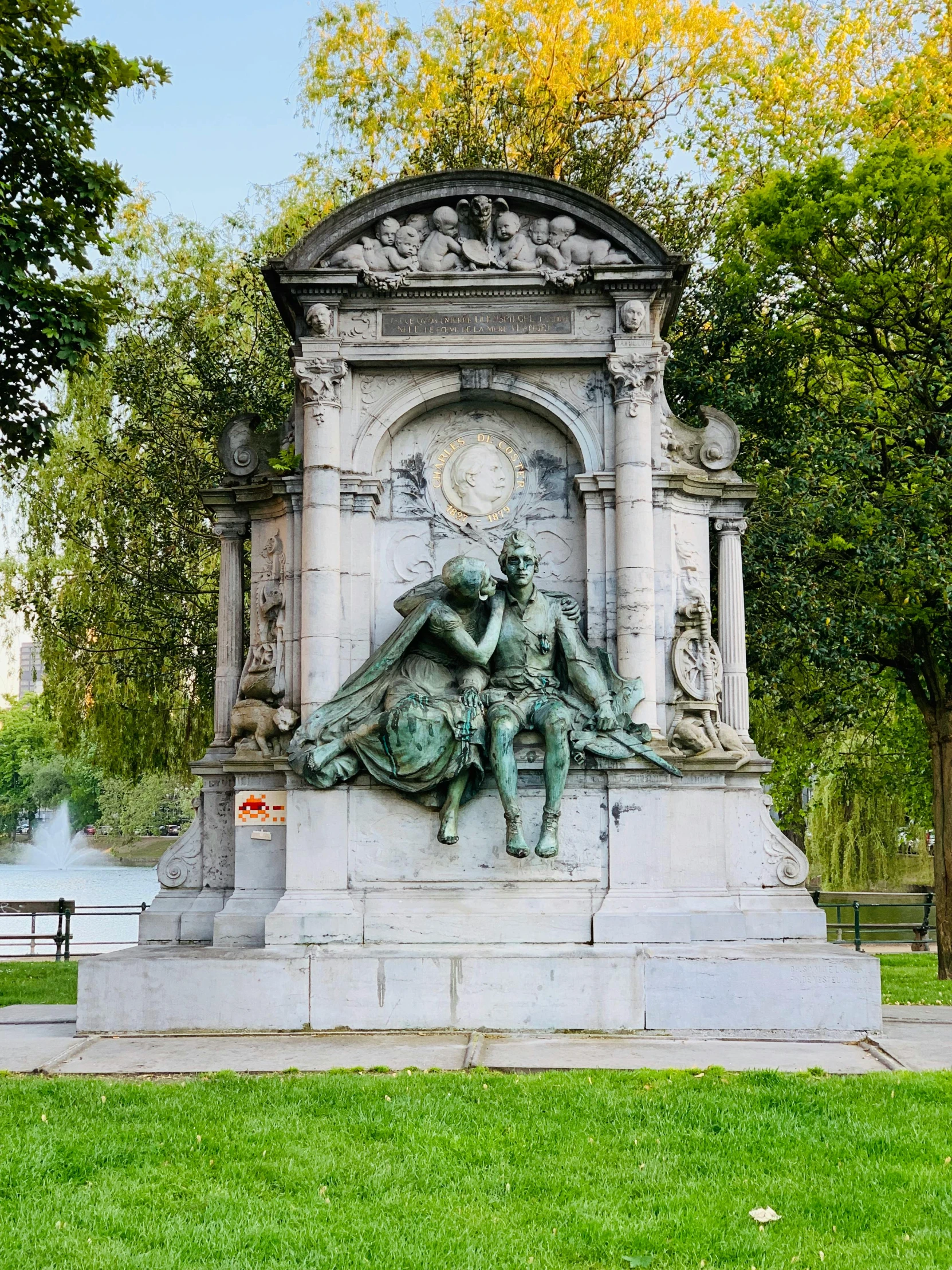 a statue on the grass near water