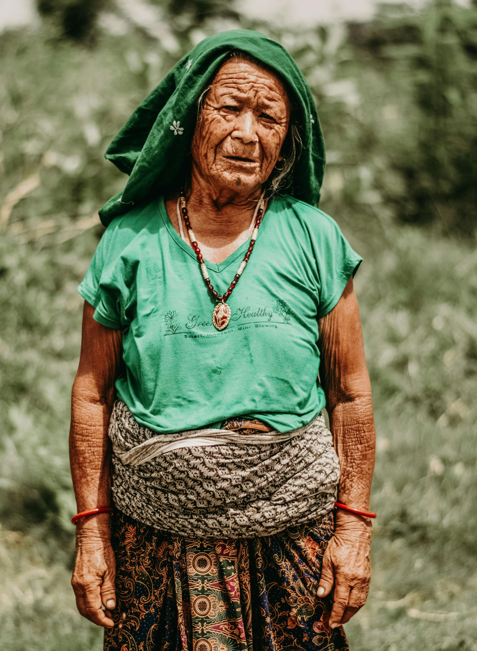 an elderly woman with green clothes, smiling, carrying a rope