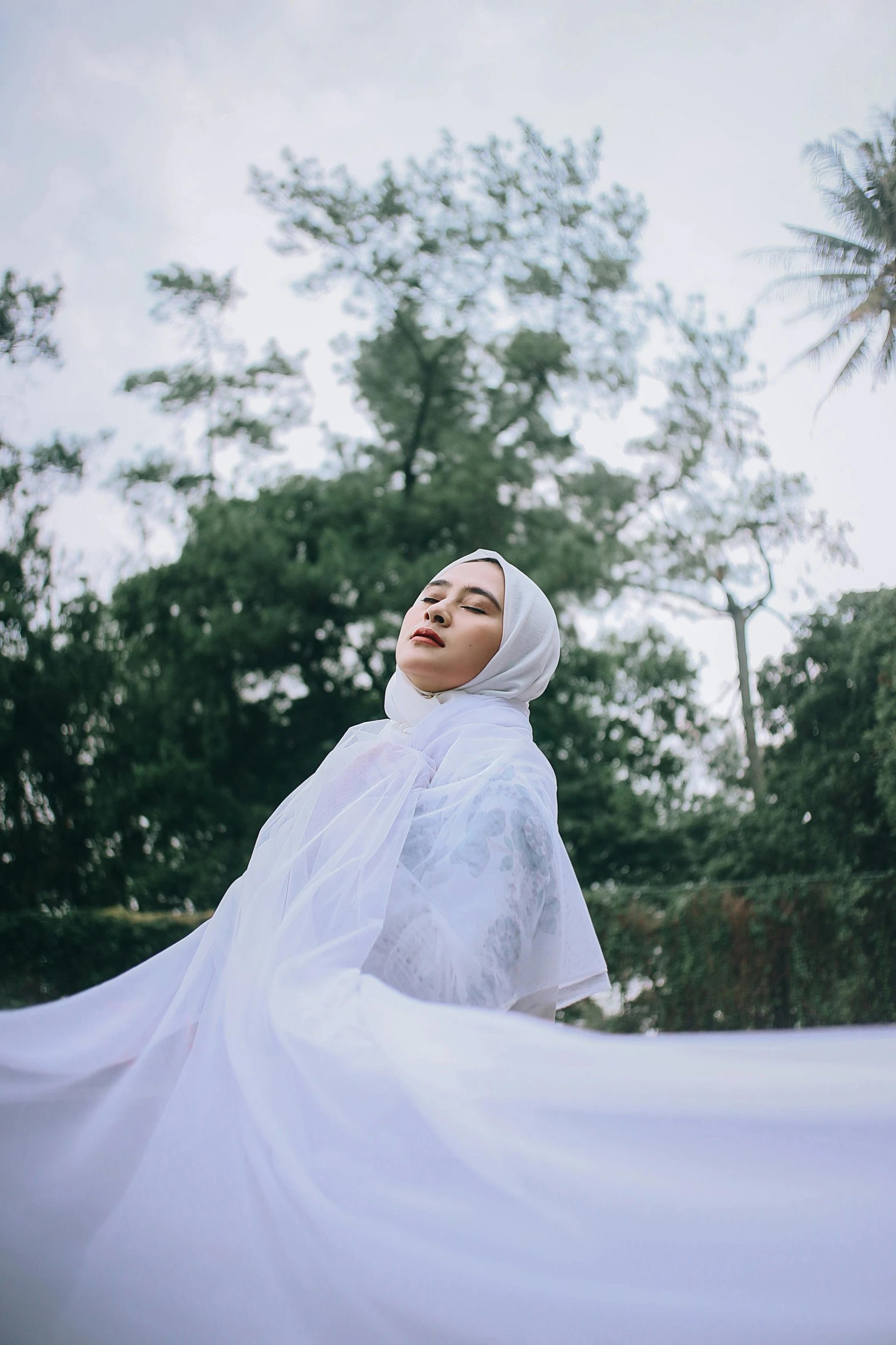 a woman in white clothes and veil holding a flower