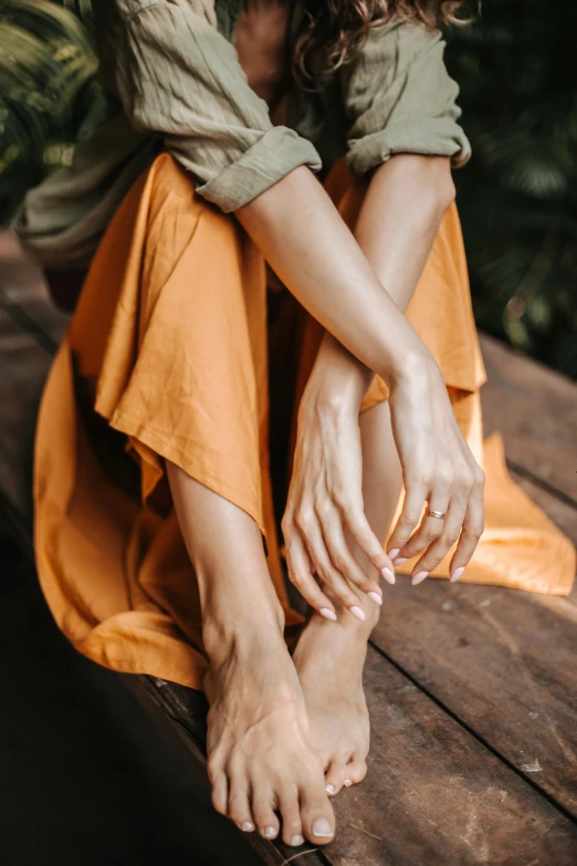 woman wearing sandals sits on a wooden plank