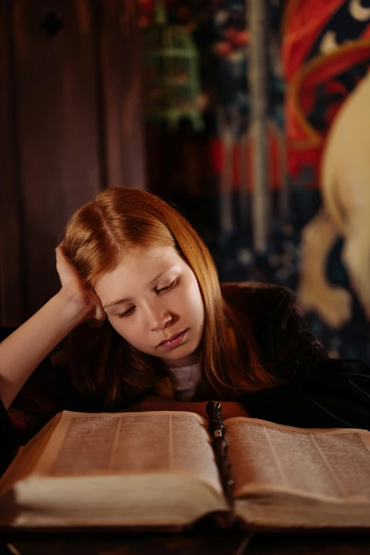 a woman with long hair sitting at a table reading a book