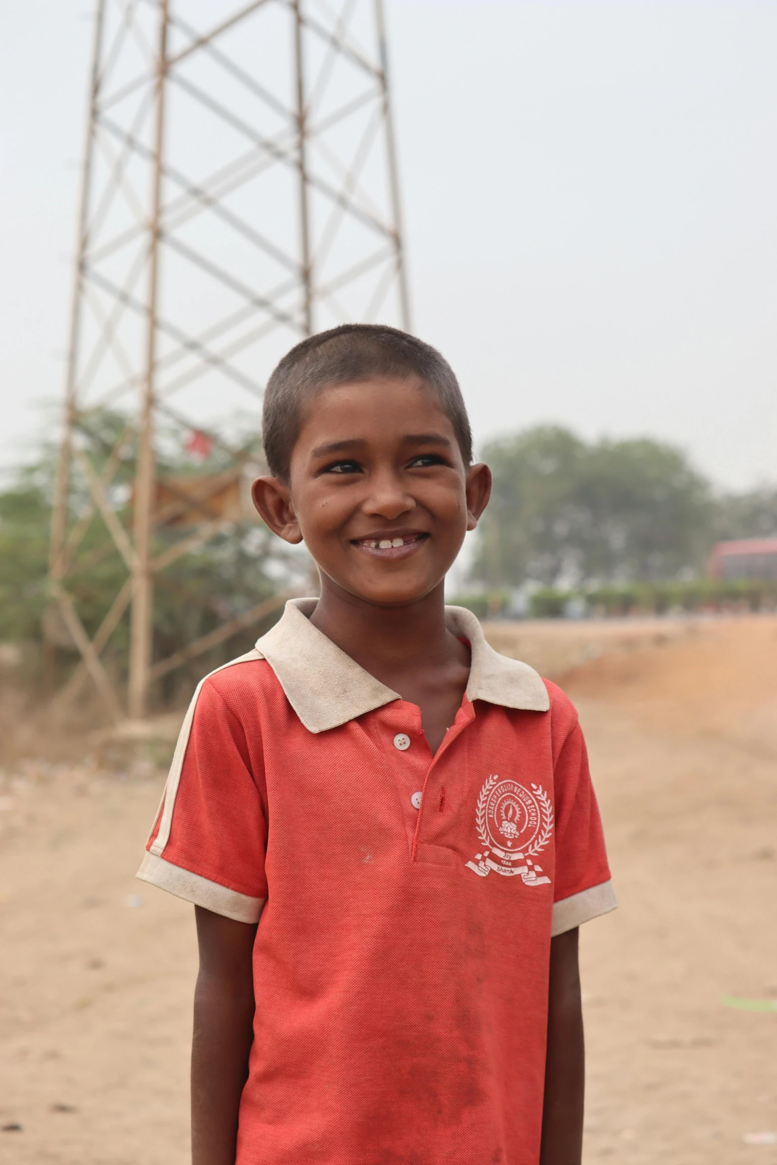 a boy in a red shirt smiles for the camera