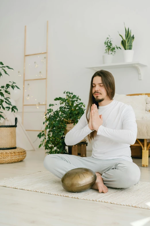 a man is sitting on a yoga mat with his hands together