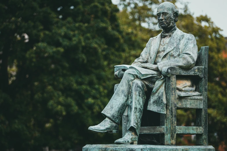 a statue of thomas garfield sits on a bench outside