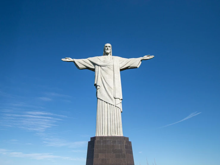 a large white statue of the christ of jesus stands against a bright blue sky