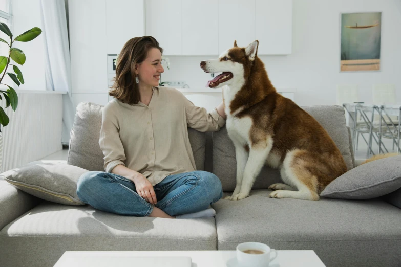 a woman is sitting on a couch with a dog