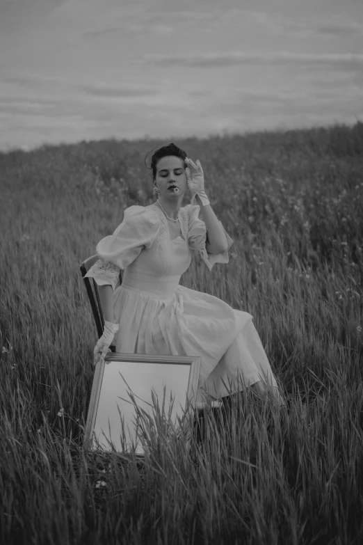 a girl in a field with a suitcase holding her hair