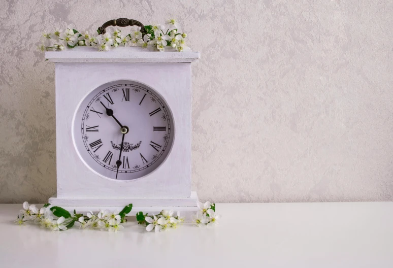 a small clock with flowers growing out of it