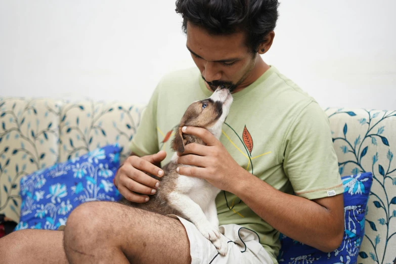 a man kisses a dog's nose while on a couch