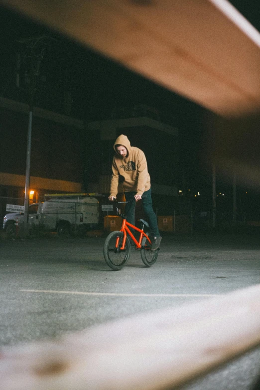 person in hooded clothing riding a bike down the street at night