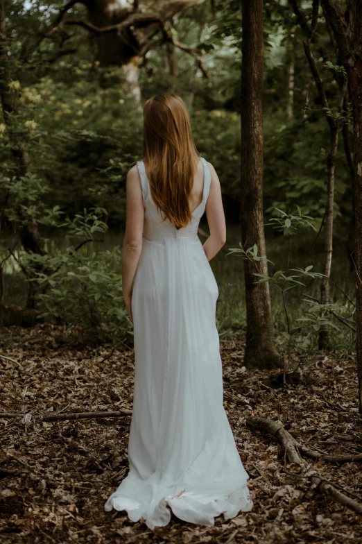 a bride standing in the woods looking back