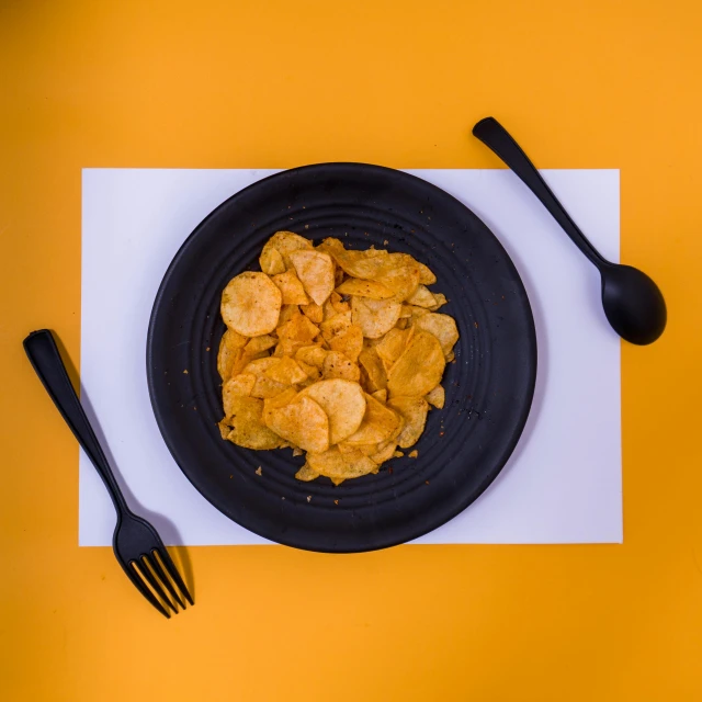 plated food next to fork and knife on a yellow table