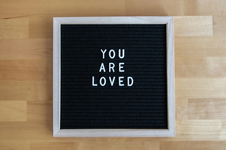 a black and white sign saying you are loved with white lettering on it