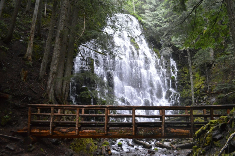 a bridge crossing a river over a small waterfall