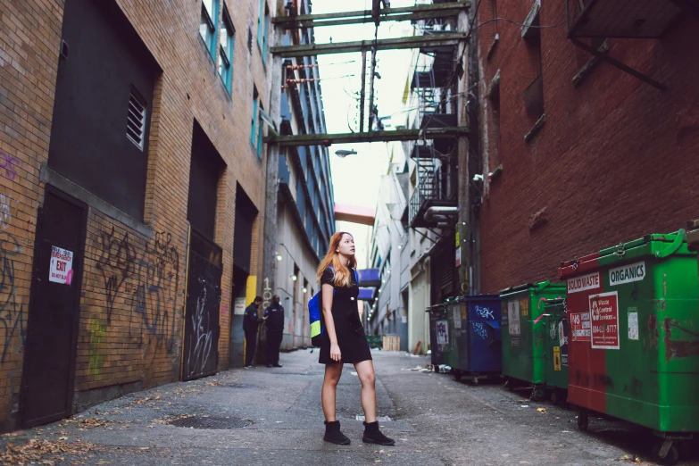 a person standing in an alley with graffiti on the walls