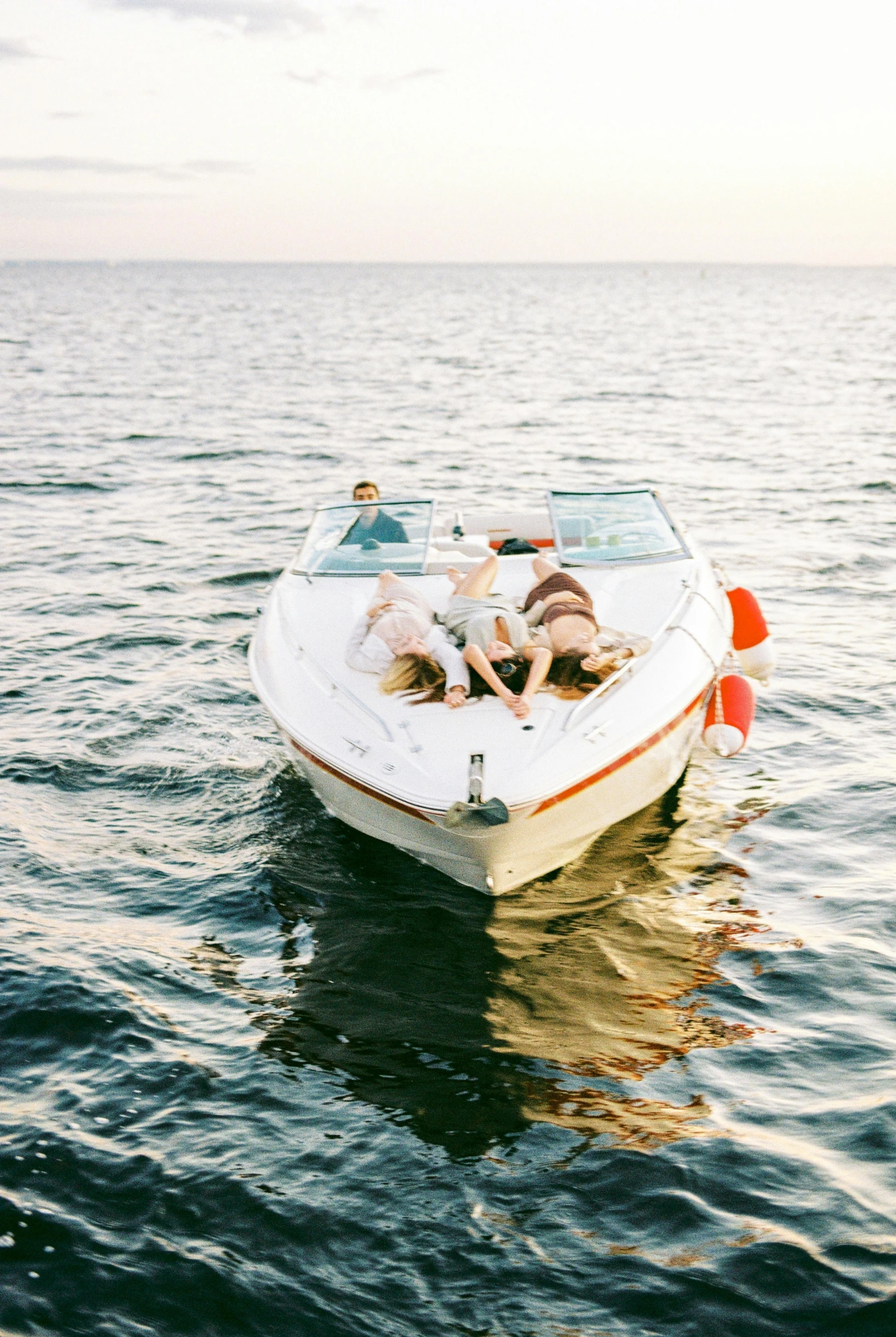 people riding in the bow of a boat on calm water