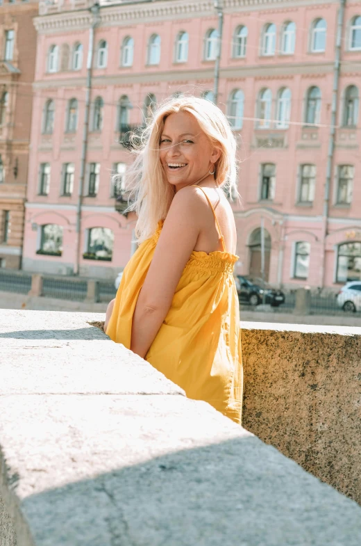 a young woman with blonde hair standing in front of buildings