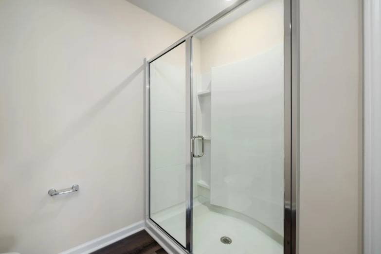 an all white bathroom with walk in shower and toilet