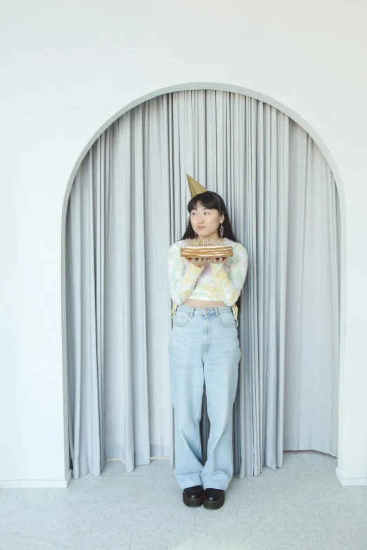 a woman standing against a curtain wearing a tiara