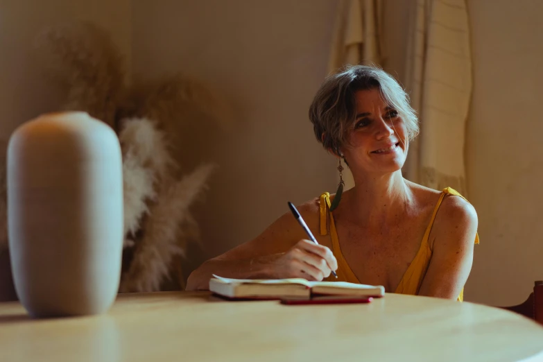 a woman at a table writing in a book