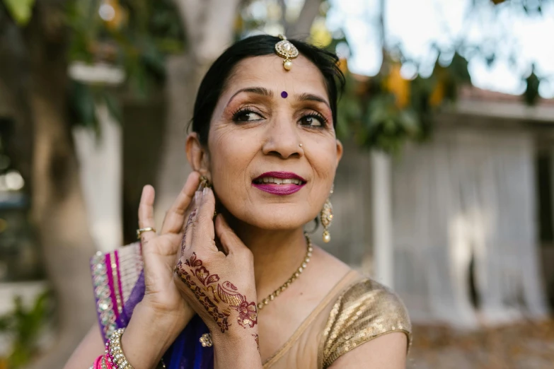 a woman smiles wearing two bangles and jewelry