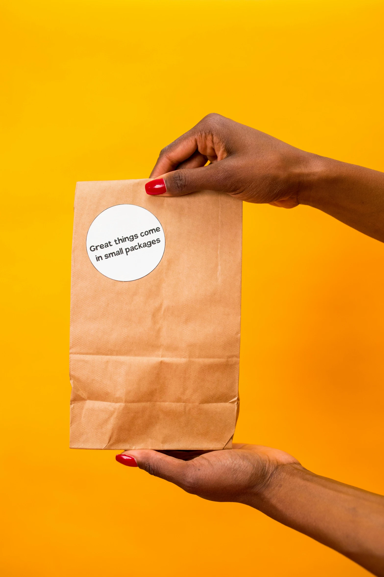 a hand holding up a paper bag with sticker