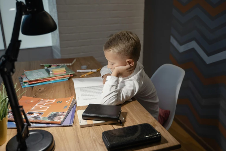 a small boy sits at a table with books