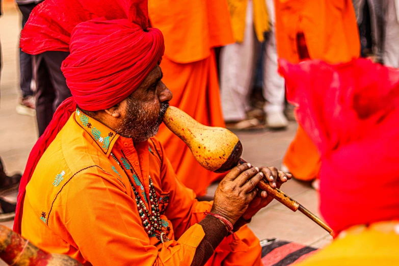 a man with a mustache and orange turban playing an instrument