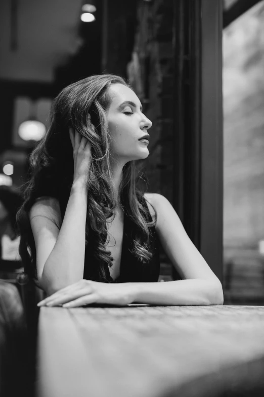 a woman sitting in a booth with her hands near her face