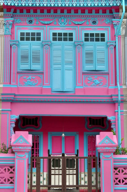an old pink and blue building is painted in the colors of pink, blue, and white