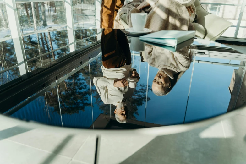 a reflection of an older man holding a cup of coffee