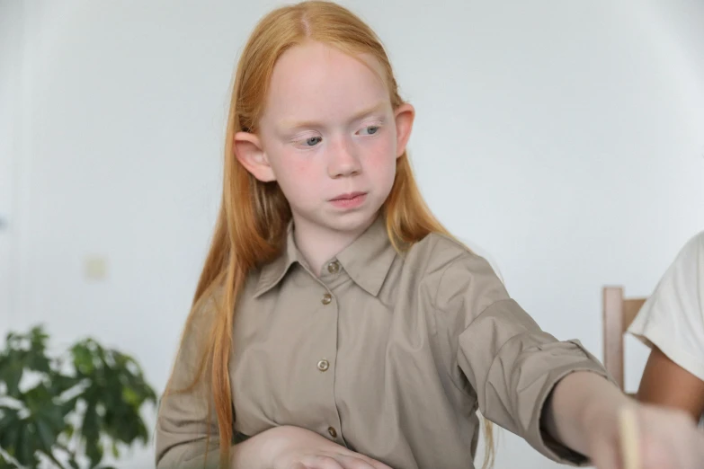 red headed  in a brown shirt playing with an object