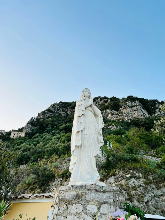 a view of a white statue on a hill with a sky background