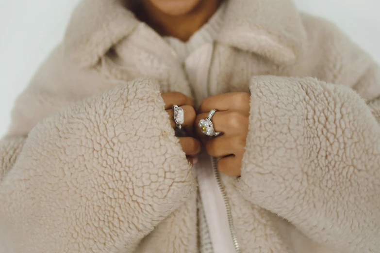 closeup of a person wearing a white coat and some rings on their fingers