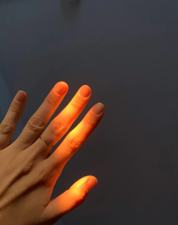 a person's hand holding the light on a table