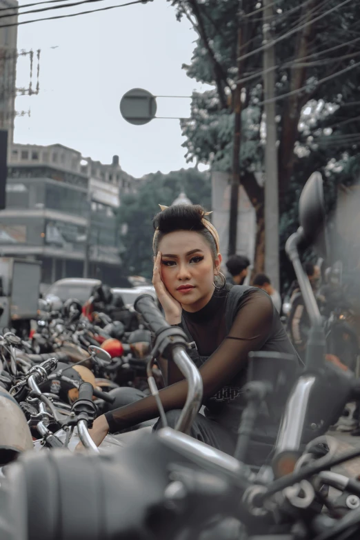 a woman sits on a black motorcycle near many parked motorcycles