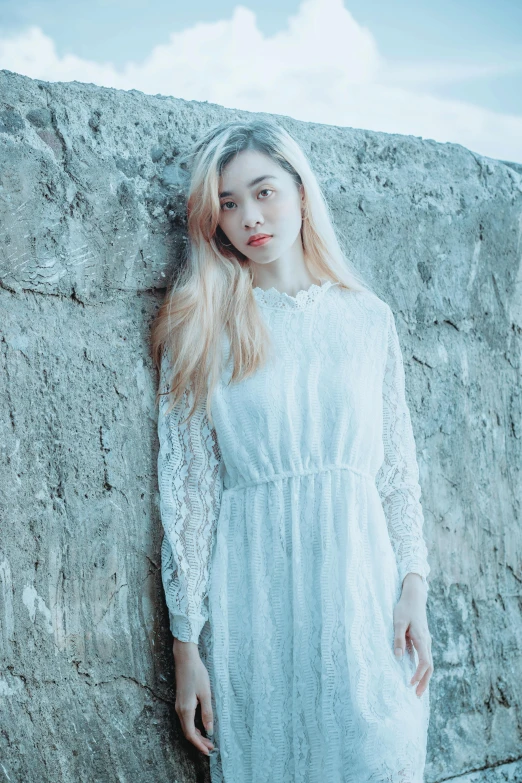 a woman in a long dress posing next to a rock