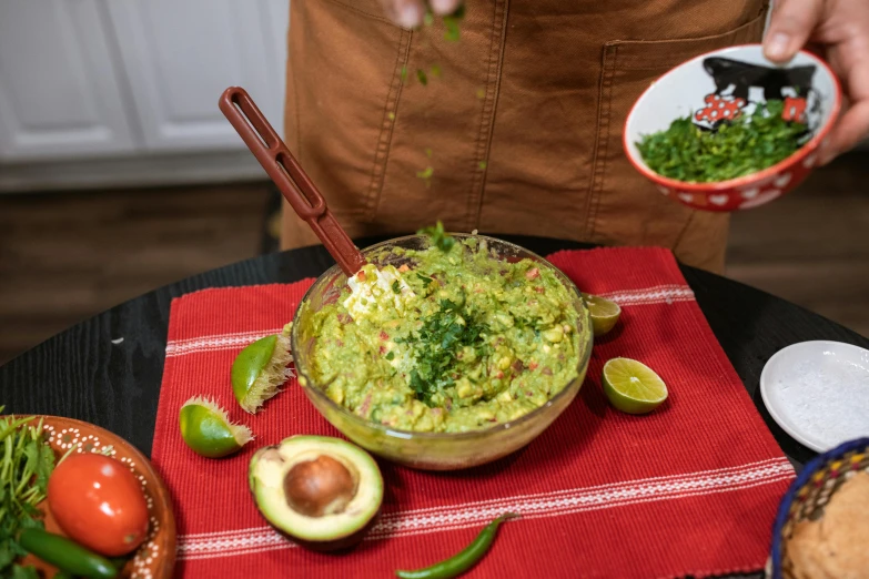 someone is putting guacamole in a bowl with spoon