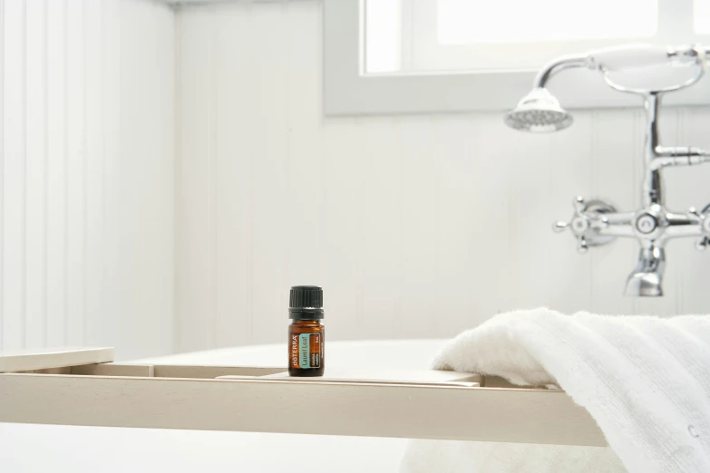 a bottle of essential oils sits on a shelf near a bath tub