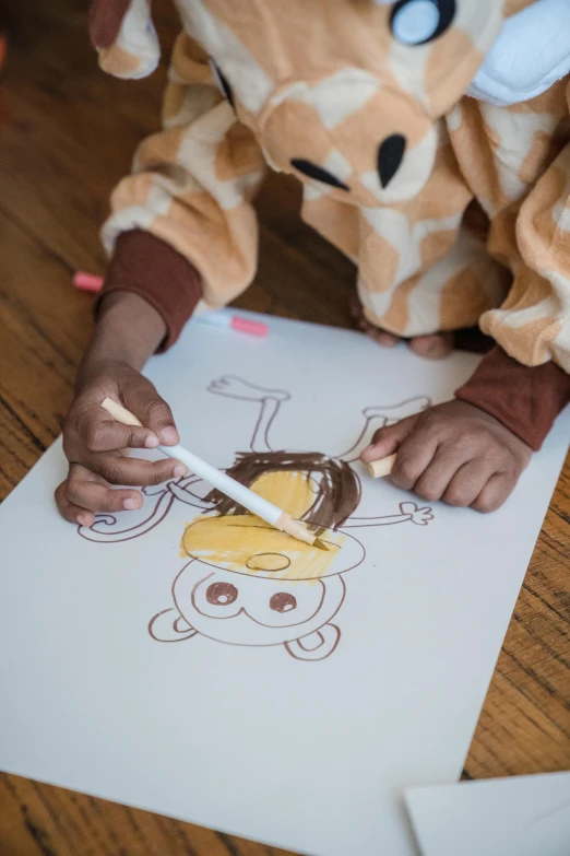 a child holding a crayon marker as they color a piece of paper